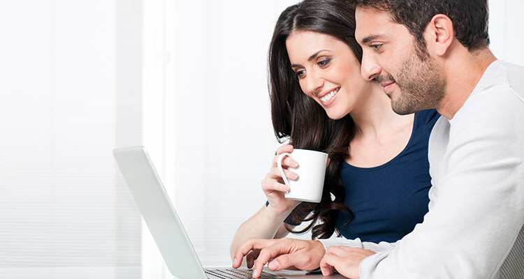 Couple looking at laptop drinking coffee