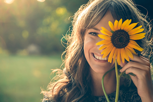 Young woman with sunflower over her eye