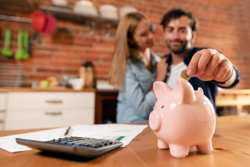 Couple Putting Coins into Piggy Bank