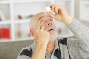 man applying eye drops