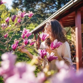 Woman enjoying the spring of her home in the garden near a blooming magnolia tree inhaling the aroma